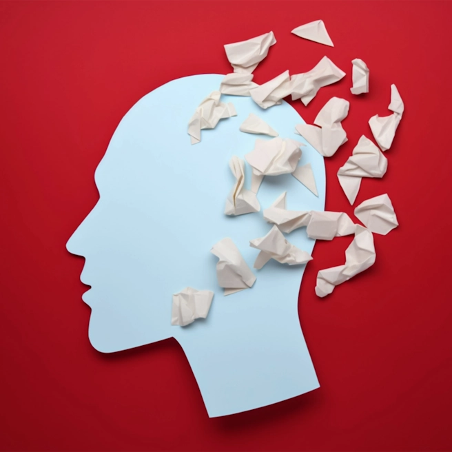 Silhouette de tête humaine bleue avec des morceaux de papier symbolisant la perte de mémoire après un traumatisme crânien