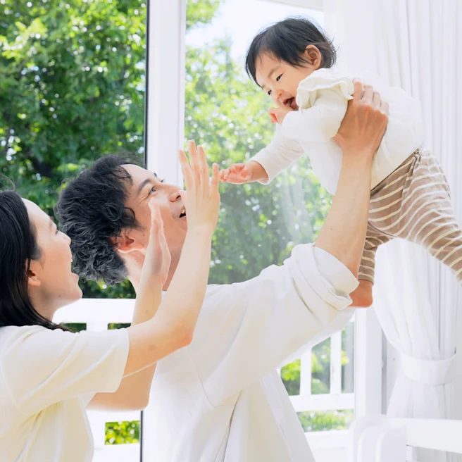 Parents jouant avec leur bébé dans un cadre lumineux, illustration d’un contexte familial autour de la prévention du syndrome du bébé secoué.