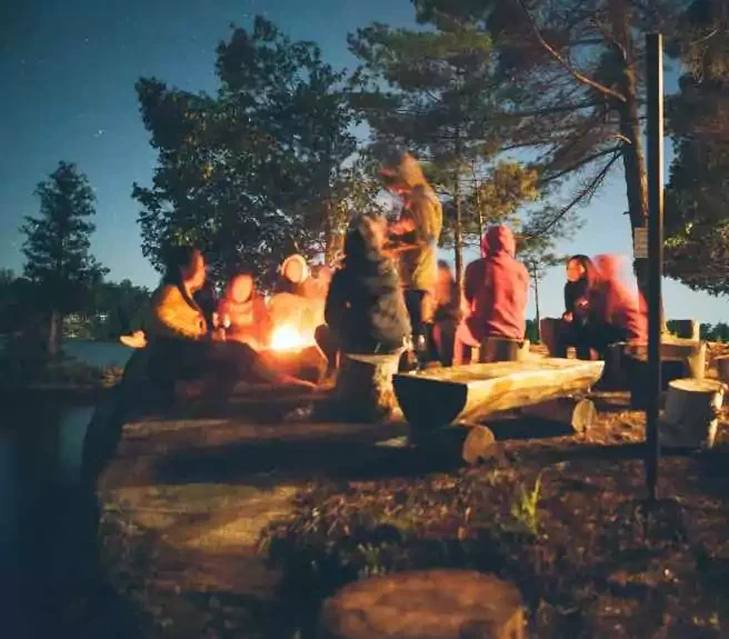 Participants réunis autour d’un feu de camp lors d’un séjour sportif organisé.